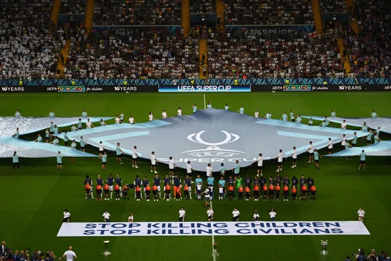 FAIXA É EXIBIDA EM JOGO DA UEFA " PAREM DE MATAR CRIANÇAS"